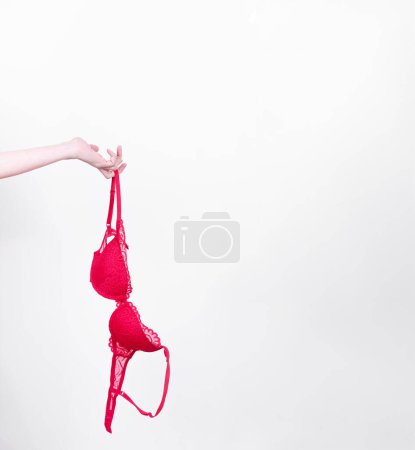 Photo for Woman hand holds red lingerie in her hand - Royalty Free Image