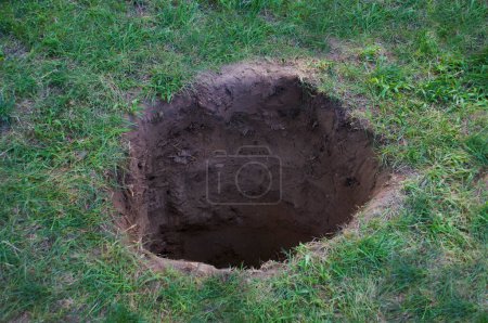 Photo for Deep dirt hole in ground or lawn - Royalty Free Image