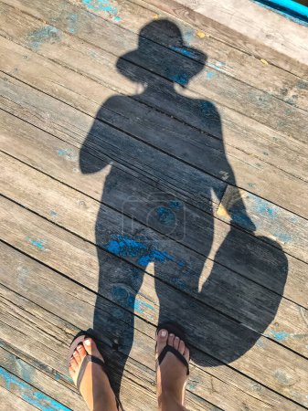 Foto de "Vista superior, foto de los pies desnudos y un par de sombras en una o de madera
" - Imagen libre de derechos