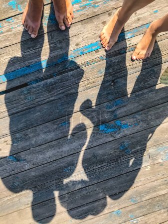 Photo for "Top view, photo of bare feet and a pair of shadows on a wooden o" - Royalty Free Image