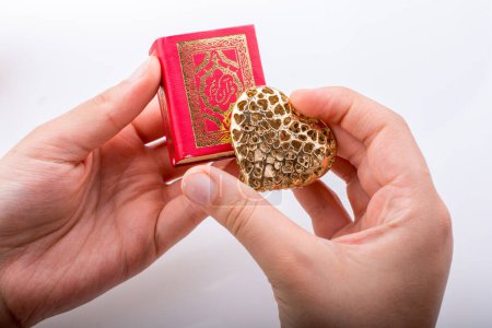 Photo for "Hand holding Heart shape  and Islamic Holy Quran " - Royalty Free Image