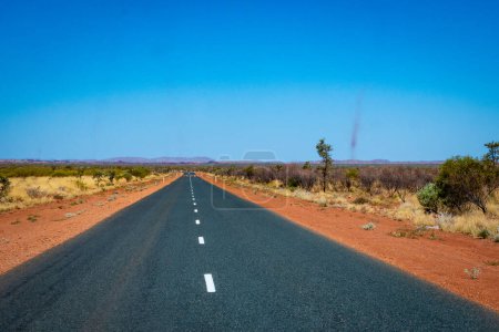 Foto de "Tormentas de polvo además de camino oscuro que conduce a través del paisaje australiano de arena roja hacia el Parque Nacional Karijini" - Imagen libre de derechos