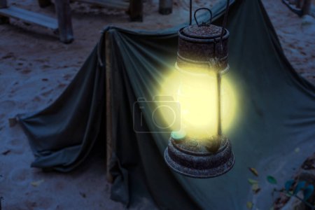 Foto de "vieja linterna iluminada oxidada que brilla luz brillante durante la noche, campamento minero, caminata de supervivencia en la naturaleza por la noche
" - Imagen libre de derechos