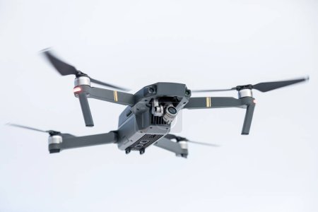 Téléchargez les photos : "le quadcopter de couleur grise avec la caméra en vol contre" - en image libre de droit