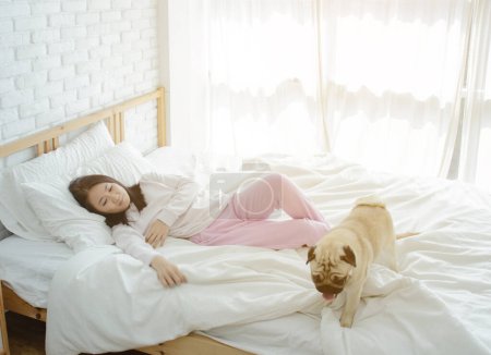 Photo for Young woman sleeping with dog in bed. - Royalty Free Image