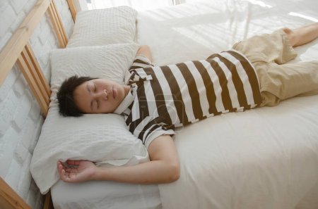 Téléchargez les photos : Asiatique homme sommeil dans lit - en image libre de droit