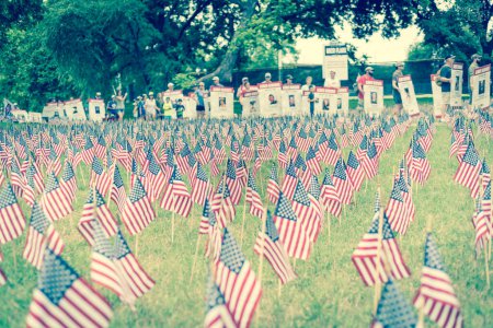Photo for "Filtered image lawn American flags with blurry row of people carry fallen soldiers banners parade" - Royalty Free Image