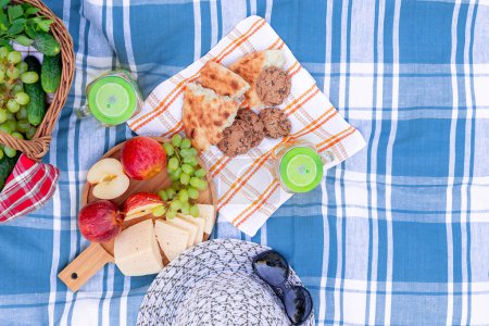Téléchargez les photos : Pique-nique sur l'herbe un jour d'été - panier, raisin, fromage, pain, pommes - un concept de loisirs d'été en plein air - en image libre de droit