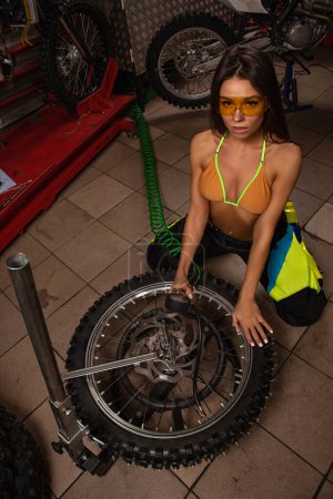Téléchargez les photos : Sexy fille dans garage pompage pneus - en image libre de droit