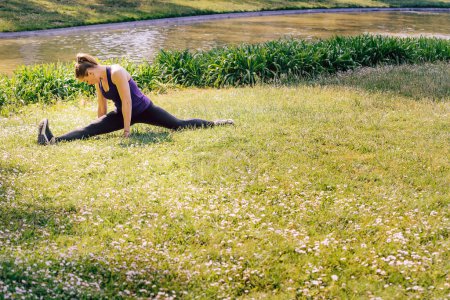 Foto de Mujer estirando las piernas en la hierba del parque th - Imagen libre de derechos