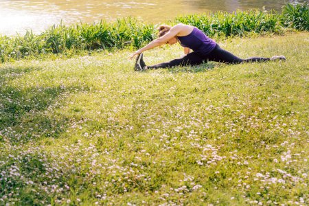 Photo for Woman doing flexibility exercises on the grass - Royalty Free Image