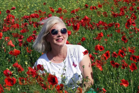 Foto de Mujer rubia impresionada por la belleza del campo con amapolas - Imagen libre de derechos