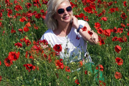 Foto de Mujer rubia impresionada por la belleza del campo con amapolas - Imagen libre de derechos
