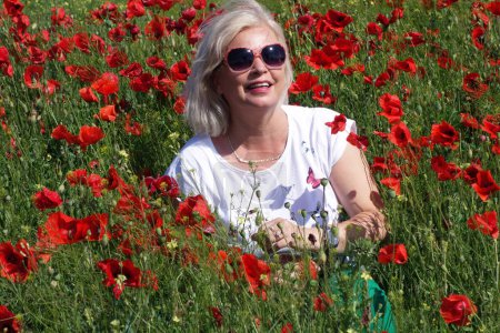 Photo for Blond woman impressed by the beauty of the field with poppies - Royalty Free Image
