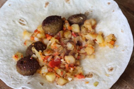 Photo for Baked falafel on a wrap with onion, paprika and potato cubes - Royalty Free Image