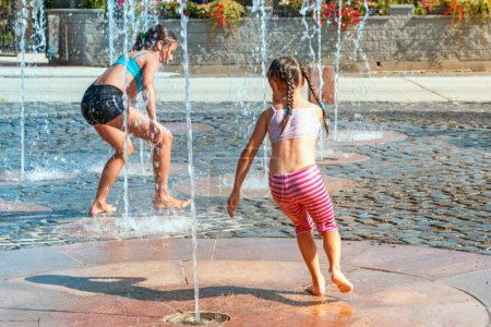 Foto de Niños jugando al aire libre en una fuente de agua en un día soleado y cálido - Imagen libre de derechos