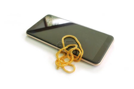 Téléchargez les photos : Collier en or et smartphone sur fond blanc - en image libre de droit