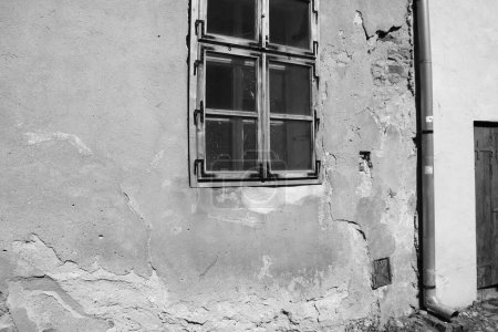 Téléchargez les photos : Vue d'une vieille maison avec des fissures sur le mur et la fenêtre, photo noir et blanc - en image libre de droit