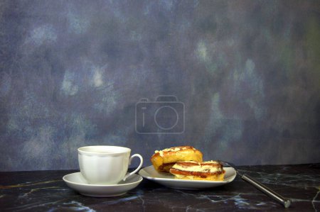 Photo for "A cup of black coffee and a saucer with two fresh cinnamon rolls." - Royalty Free Image
