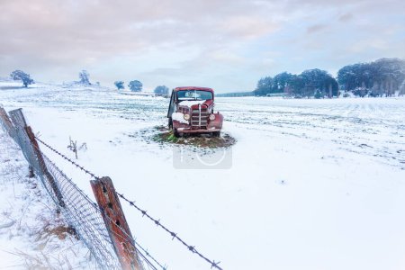Téléchargez les photos : Vieille voiture rouillée se trouve dans un champ rural enneigé - en image libre de droit