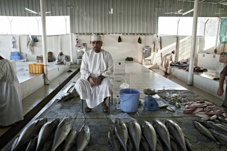 Foto de Viejo pescador omani vendiendo su captura en el viejo mercado de pescado - Imagen libre de derechos