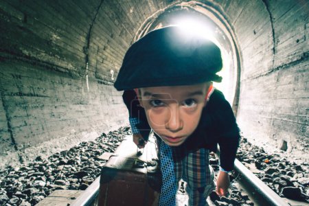 Téléchargez les photos : Enfant marchant sur la route ferroviaire avec siutcase vintage - en image libre de droit