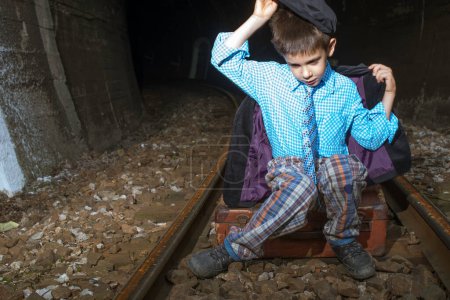 Téléchargez les photos : Enfant en vêtements vintage assis sur la route ferroviaire - en image libre de droit
