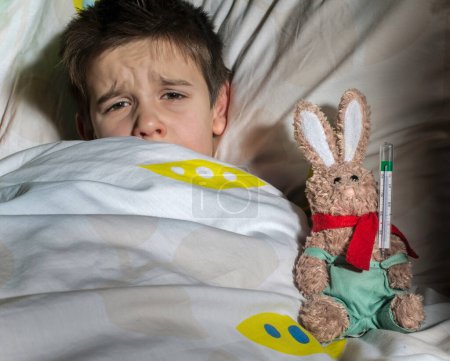 Téléchargez les photos : Enfant malade au lit avec ours en peluche - en image libre de droit