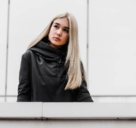 Photo for Young girl with blond hair and black clothes against a gray building - Royalty Free Image