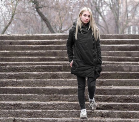 Téléchargez les photos : Jeune fille aux cheveux blonds en vêtements noirs descend la pierre - en image libre de droit