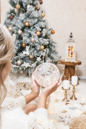 Téléchargez les photos : Une femme tient une boule de Noël scintillante pour l'arbre - en image libre de droit
