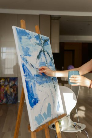 Foto de Mujer pinta un cuadro sobre lienzo en su sala de estar - Imagen libre de derechos