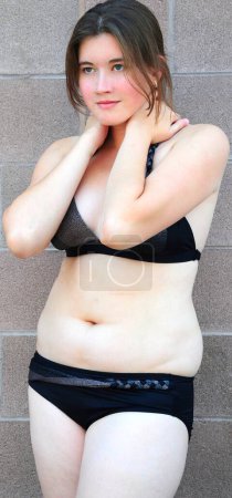 Photo for Woman in black bikini posing on camera while standing at wall - Royalty Free Image