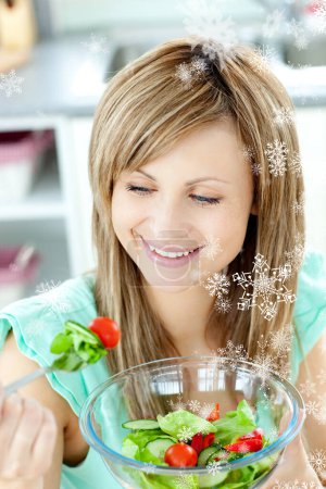 Photo for "Young woman eating a salad in the kitchen" - Royalty Free Image