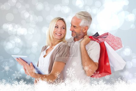 Photo for "Composite image of happy couple with shopping bags and tablet pc" - Royalty Free Image