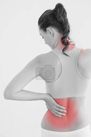Photo for "Rear view of a toned woman with back pain against wall" - Royalty Free Image
