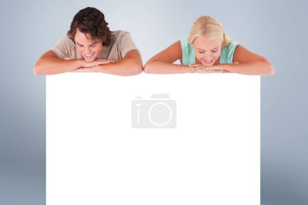 Photo pour "Composite image of happy couple leaning on a whiteboard" - image libre de droit