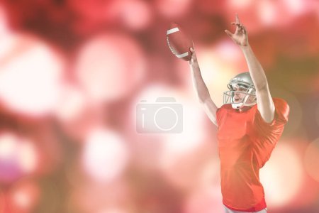Téléchargez les photos : "Image composite du footballeur américain tenant le ballon tout en pointant vers le haut" - en image libre de droit