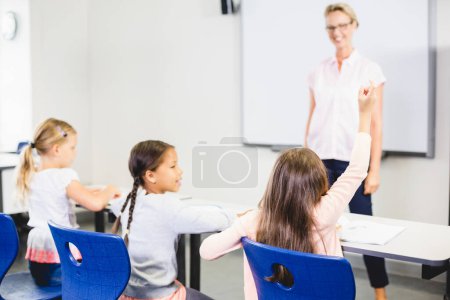Téléchargez les photos : Des enfants lèvent la main en classe - en image libre de droit