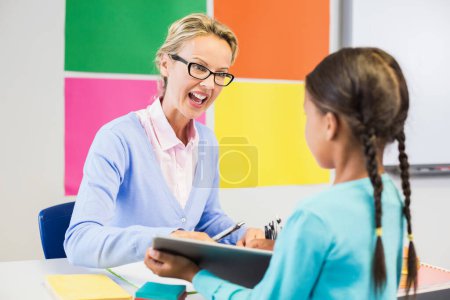 Photo for Teacher interacting with schoolgirl in classroom - Royalty Free Image