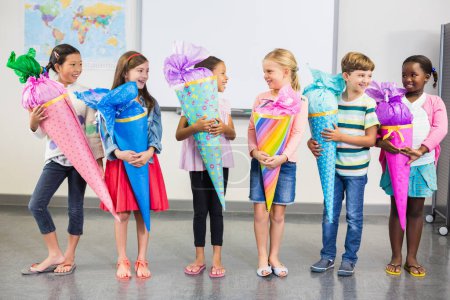 Photo for Happy kids holding gifts in classroom - Royalty Free Image