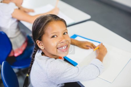Téléchargez les photos : Écolière souriant dans salle de classe - en image libre de droit