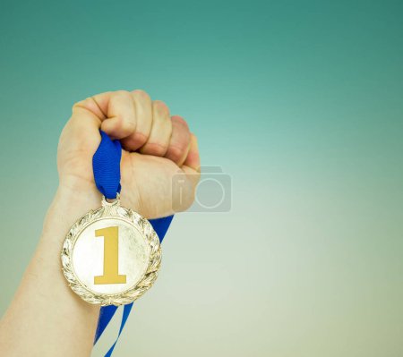 Foto de "Imagen compuesta de primer plano de la mano sosteniendo la medalla de oro olímpica" - Imagen libre de derechos