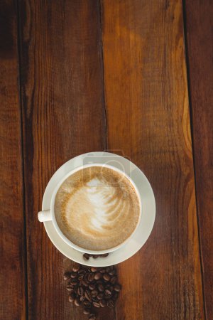 Foto de Cappuccino con granos de café en la mesa - Imagen libre de derechos