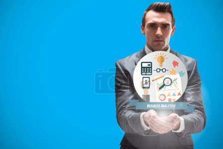 Photo for Businessman holding business icons on blue background - Royalty Free Image