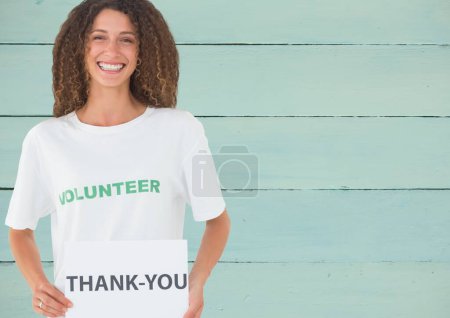 Foto de Voluntario sonriente mostrando tarjeta de agradecimiento contra fondo de madera - Imagen libre de derechos