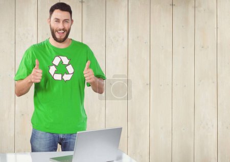 Photo for Volunteer thumbs up with computer against wooden background - Royalty Free Image