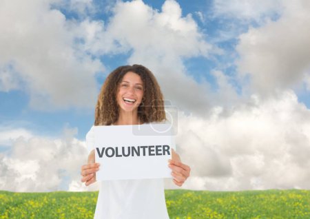 Foto de Voluntario sonriente sosteniendo pizarra blanca contra fondo de campo - Imagen libre de derechos