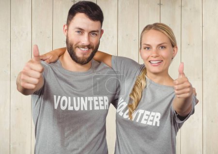 Photo for Couple of smiling volunteers thumb up against wooden background - Royalty Free Image