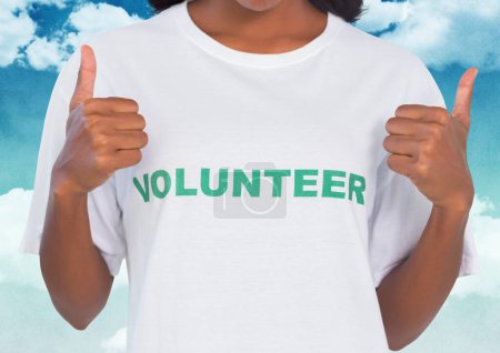 Photo for Happy volunteer with thumbs up against sky background - Royalty Free Image